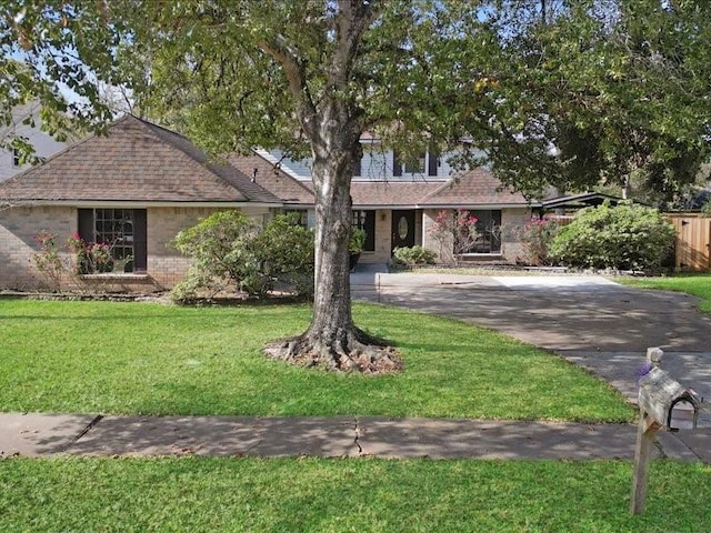 ranch-style home with brick siding, a front lawn, and a shingled roof