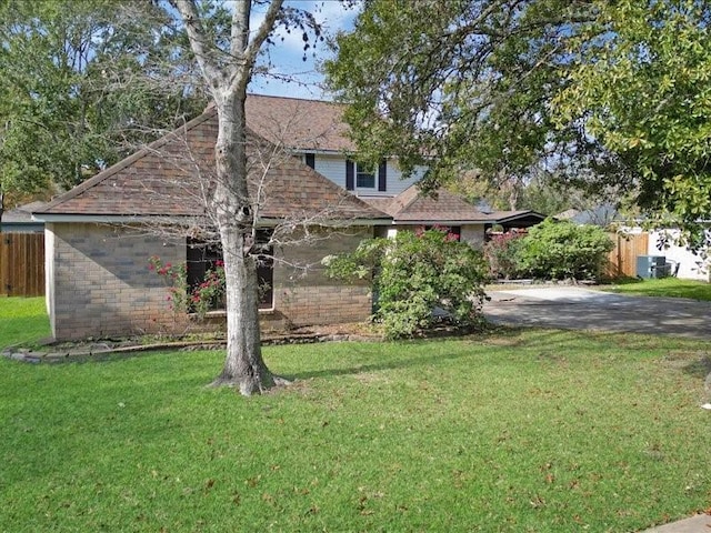 view of front of house with a shingled roof, a front yard, and fence