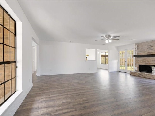 unfurnished living room featuring baseboards, a fireplace, dark wood-style flooring, and a ceiling fan