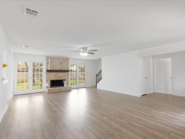 unfurnished living room featuring visible vents, a brick fireplace, baseboards, ceiling fan, and wood finished floors