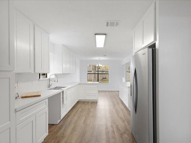 kitchen with visible vents, white cabinets, a peninsula, and stainless steel fridge with ice dispenser