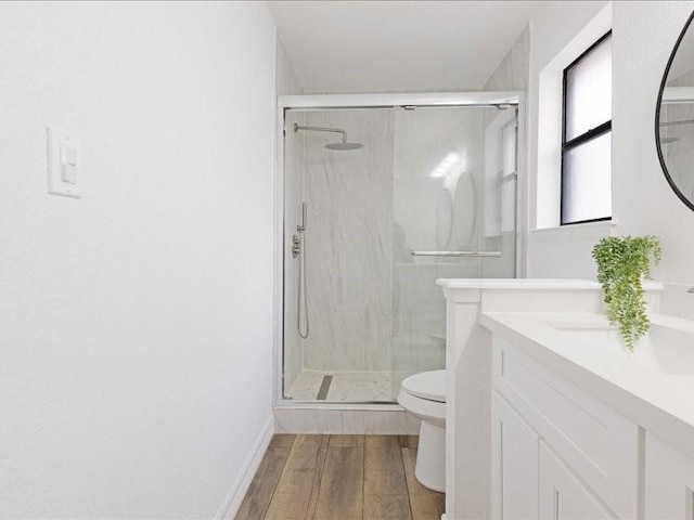 bathroom featuring double vanity, toilet, wood finished floors, and a shower stall