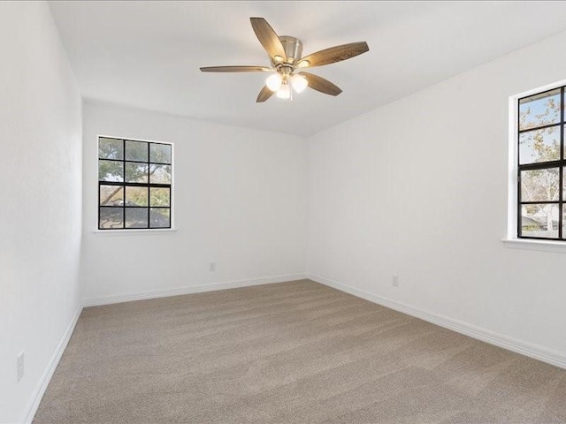 unfurnished room with baseboards, plenty of natural light, light colored carpet, and a ceiling fan