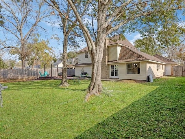 back of house with french doors, roof with shingles, a yard, and fence