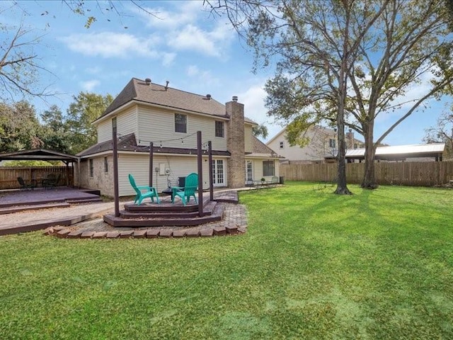 back of house featuring a patio, a yard, a fenced backyard, a chimney, and a gazebo