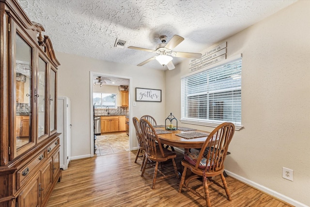 dining space with light wood-type flooring, ceiling fan, and sink