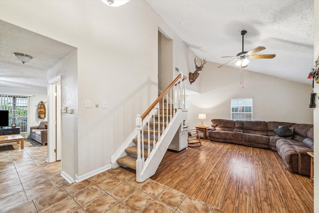 living room featuring tile patterned flooring, a textured ceiling, ceiling fan, and lofted ceiling