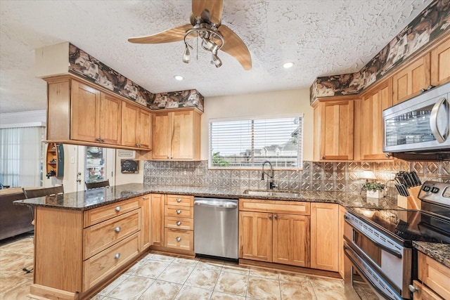 kitchen with kitchen peninsula, sink, stainless steel appliances, and a textured ceiling