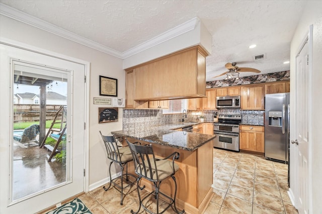 kitchen featuring kitchen peninsula, dark stone counters, a textured ceiling, and appliances with stainless steel finishes