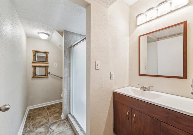 bathroom with vanity, an enclosed shower, and a textured ceiling