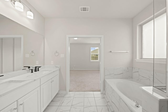 bathroom with vanity and tiled tub