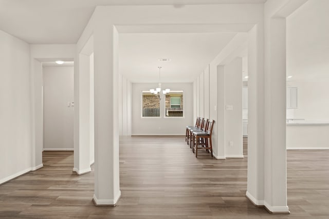 corridor with dark wood-type flooring and a notable chandelier