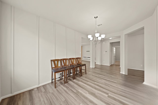 dining area featuring a chandelier, hardwood / wood-style floors, and a baseboard heating unit