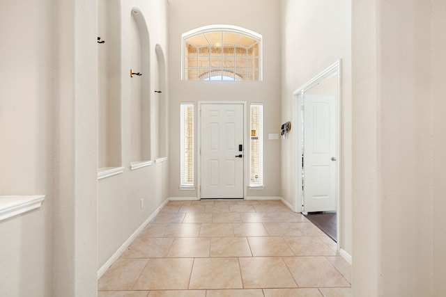 entryway with light tile patterned floors and a towering ceiling