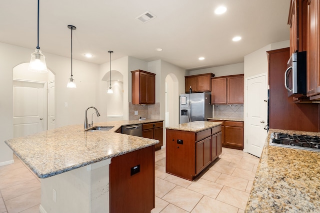 kitchen with decorative backsplash, appliances with stainless steel finishes, sink, decorative light fixtures, and a center island