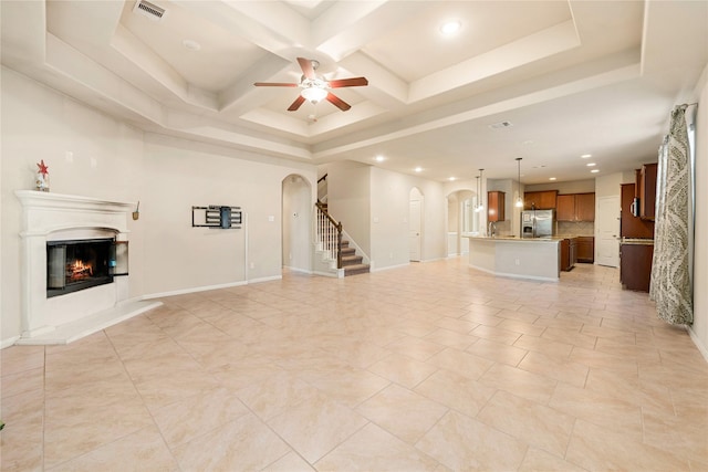 unfurnished living room featuring ceiling fan, beamed ceiling, and coffered ceiling