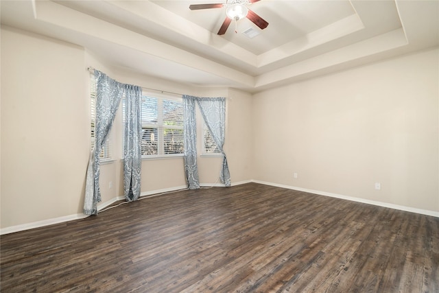 unfurnished room with a tray ceiling, dark hardwood / wood-style floors, and ceiling fan