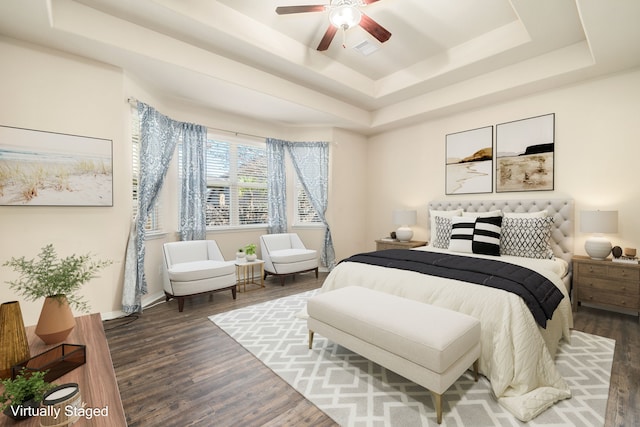 bedroom with a raised ceiling, ceiling fan, and dark hardwood / wood-style floors