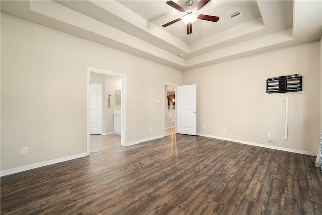 spare room with dark hardwood / wood-style floors, a raised ceiling, and ceiling fan