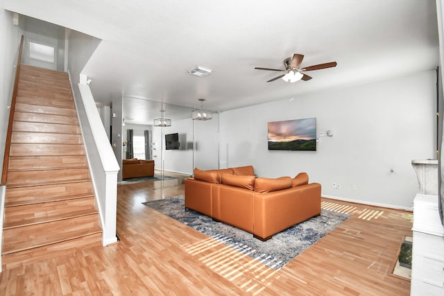 living room with wood-type flooring and ceiling fan with notable chandelier