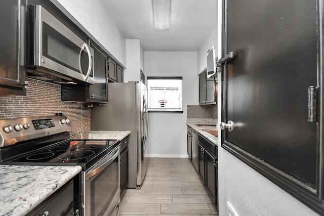 kitchen with light stone countertops, stainless steel appliances, and tasteful backsplash