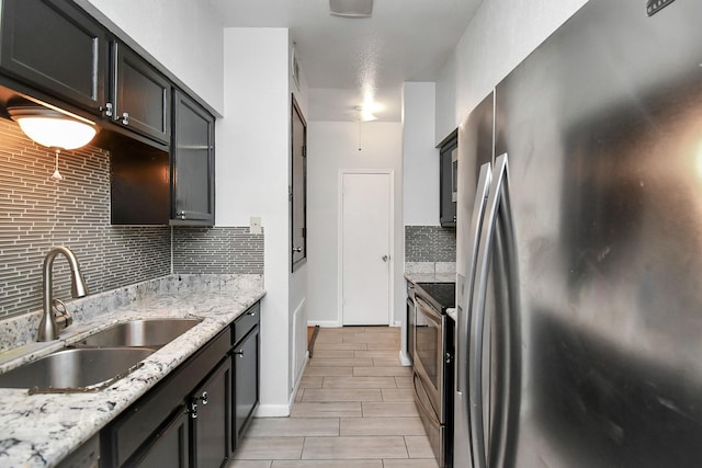 kitchen featuring light stone countertops, appliances with stainless steel finishes, backsplash, and sink