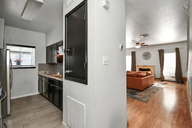 kitchen featuring decorative backsplash, stainless steel fridge, ceiling fan, sink, and light hardwood / wood-style floors