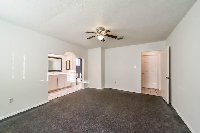 carpeted empty room featuring ceiling fan and a textured ceiling