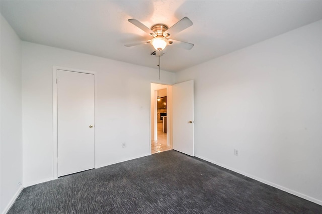 unfurnished bedroom featuring ceiling fan, a closet, and dark carpet