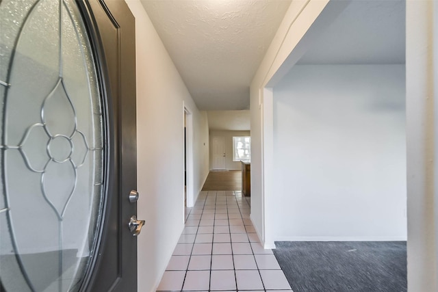 hall featuring a textured ceiling and light tile patterned flooring