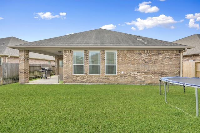 rear view of house featuring a yard, a trampoline, and a patio area