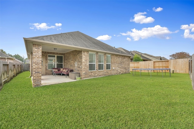 rear view of property with outdoor lounge area, a patio area, a trampoline, and a lawn