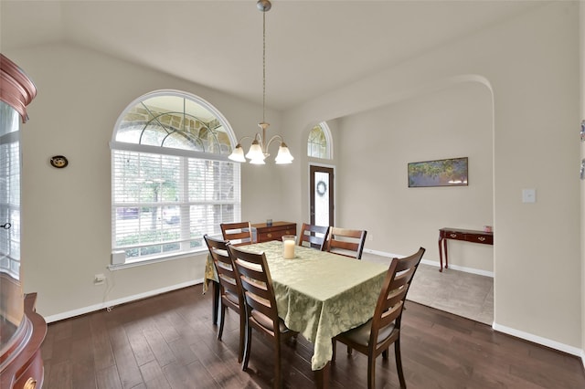 dining space with dark hardwood / wood-style flooring, lofted ceiling, and an inviting chandelier