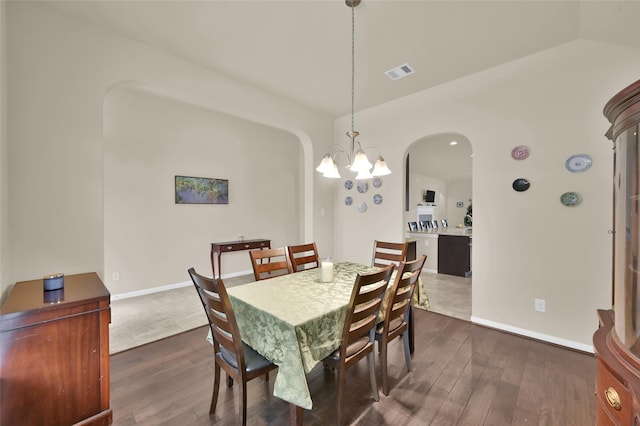 dining room with vaulted ceiling, dark hardwood / wood-style floors, and an inviting chandelier