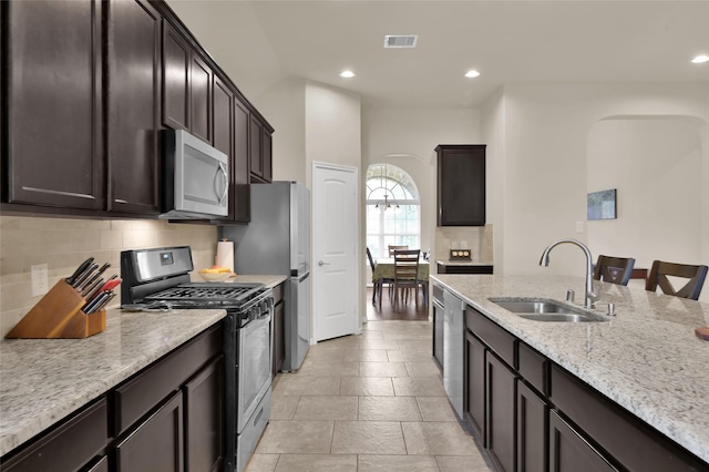 kitchen with sink, stainless steel appliances, tasteful backsplash, light stone counters, and a breakfast bar area