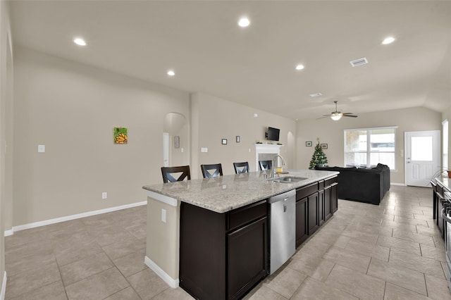 kitchen featuring a kitchen breakfast bar, stainless steel dishwasher, ceiling fan, sink, and an island with sink