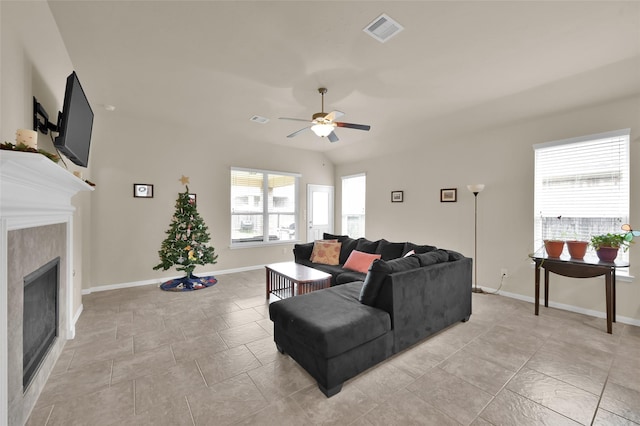 living room featuring ceiling fan and a tiled fireplace