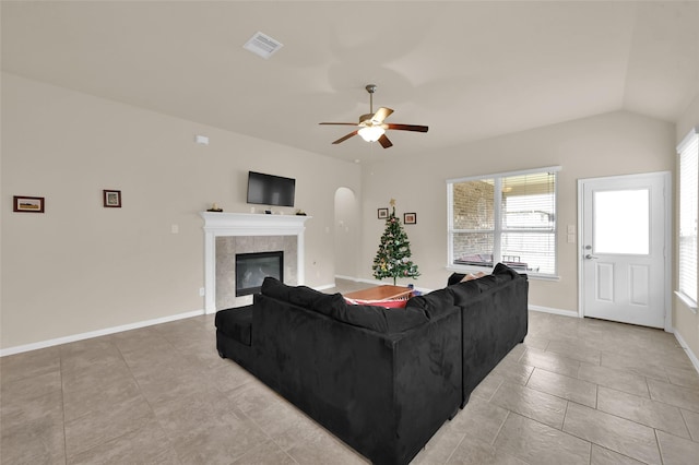 tiled living room featuring a fireplace, ceiling fan, and lofted ceiling