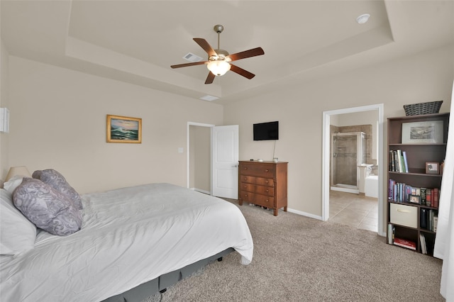 bedroom featuring ceiling fan, connected bathroom, and a tray ceiling