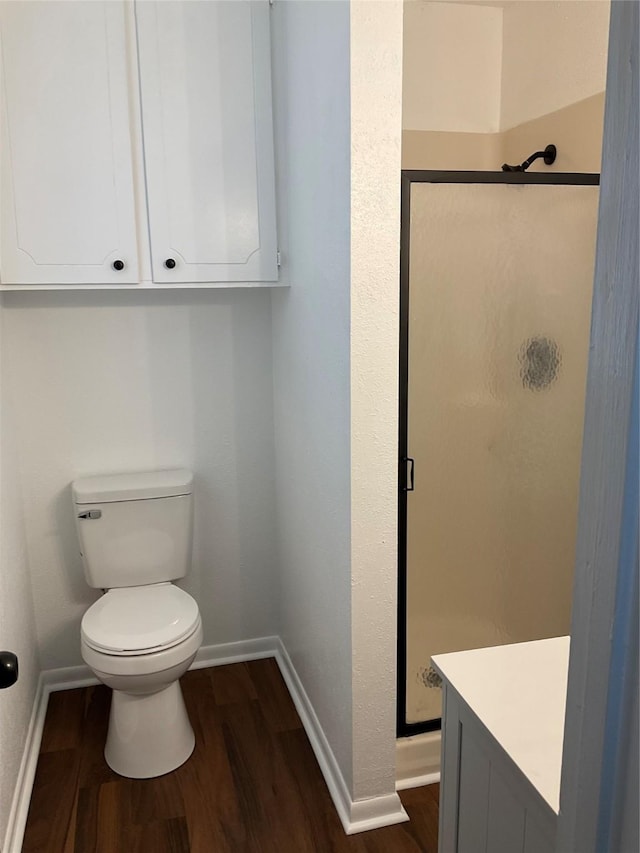 bathroom featuring vanity, hardwood / wood-style floors, a shower with door, and toilet