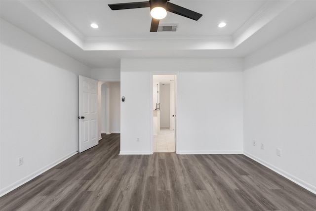 unfurnished bedroom with a raised ceiling, ceiling fan, dark hardwood / wood-style floors, and ornamental molding