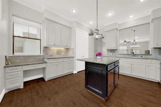 kitchen with decorative light fixtures, a kitchen island, white cabinetry, and sink