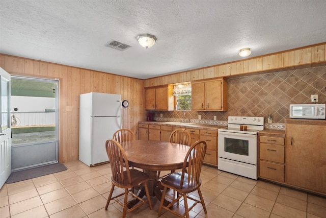 kitchen with tasteful backsplash, white appliances, a textured ceiling, and light tile patterned floors