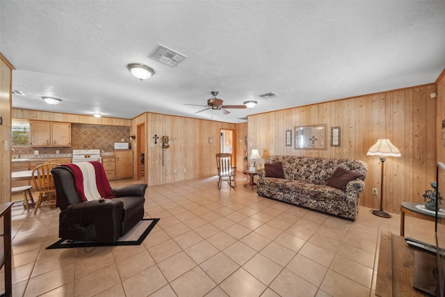 living room featuring ceiling fan, sink, light tile patterned floors, and a textured ceiling