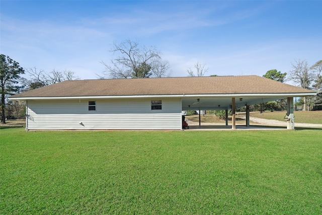 rear view of property with a carport and a yard