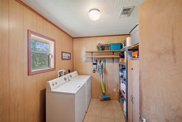 laundry area featuring wood walls, a textured ceiling, washer and clothes dryer, light tile patterned floors, and ornamental molding