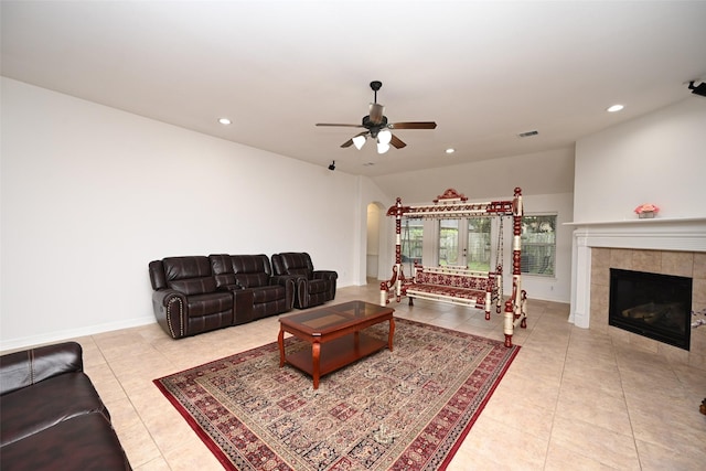 tiled living room with a tile fireplace and ceiling fan