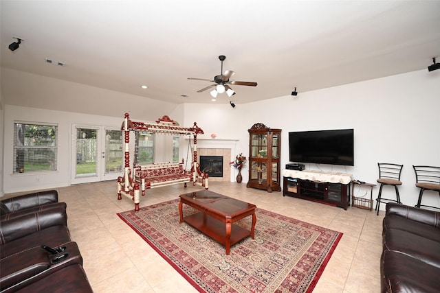 tiled living room with ceiling fan and a tiled fireplace