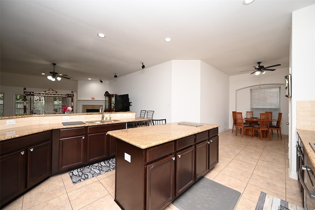 kitchen with sink, light tile patterned floors, dark brown cabinets, and a kitchen island