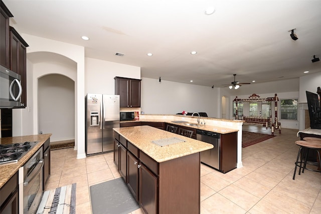 kitchen with ceiling fan, a center island, kitchen peninsula, dark brown cabinets, and black appliances